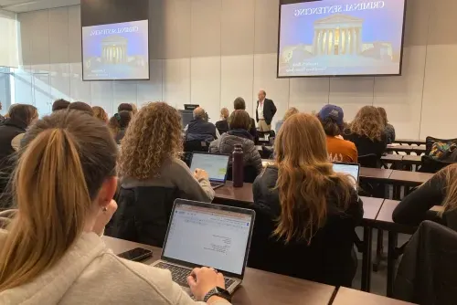 Several students in a lecture on Criminal Sentencing, focused on their laptops, engaged in a learning activity together