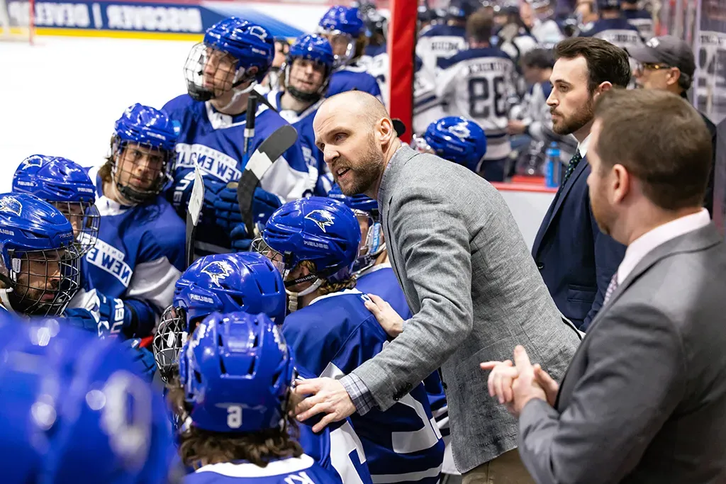 Hockey coach speaking to the U N E hockey team during a game