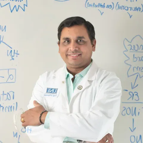 Portrait of Sri Mohan against a whiteboard with chemical formulas